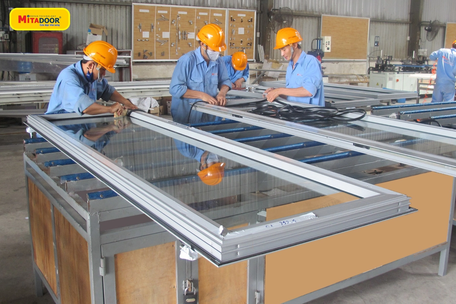 Hình ảnh nhân viên kỹ thuật đang hoàn thiện cửa nhôm kính tại nhà máy sản xuất Mitadoor