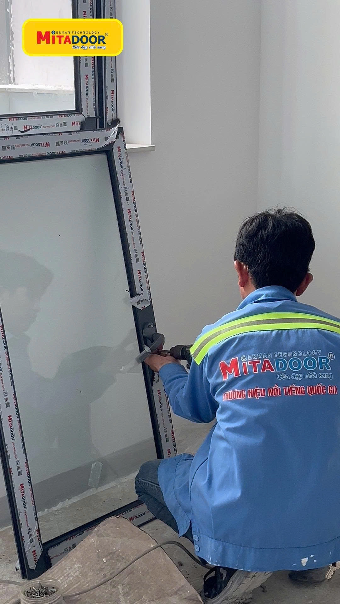 Kỹ thuật viên Mitadoor lắp tay nắm cửa sổ nhôm kính tại công trình